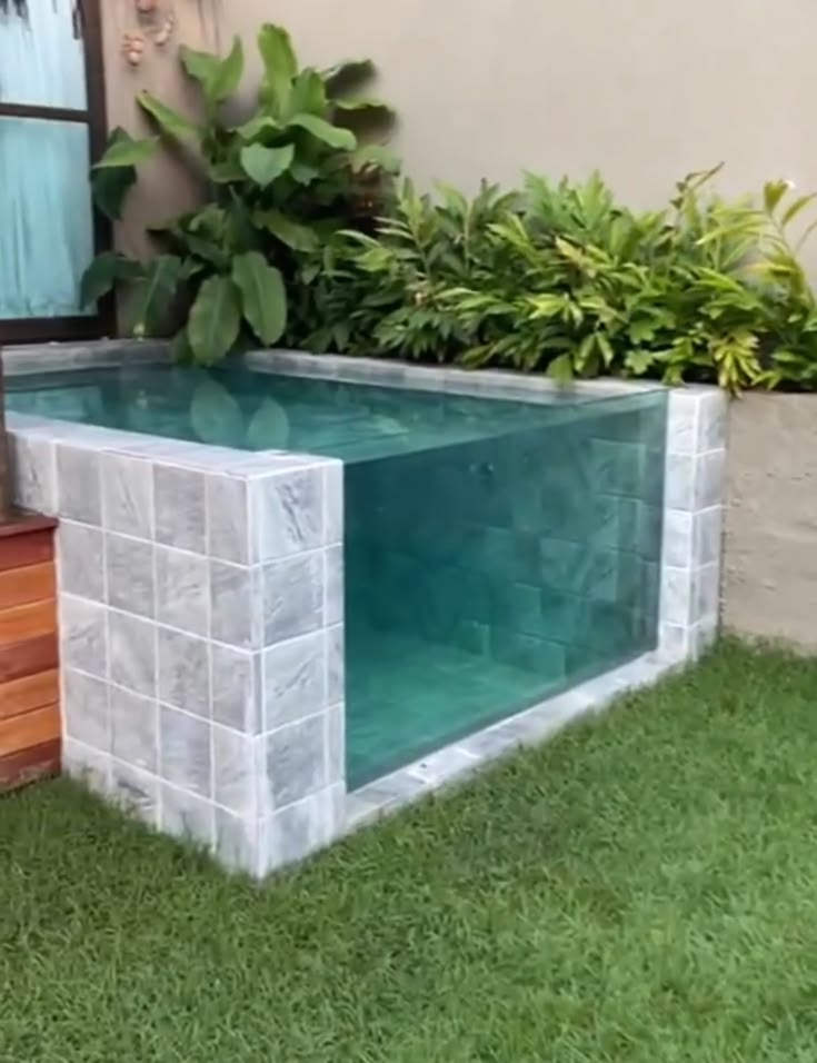 Piscina compacta com parede de vidro integrada ao jardim